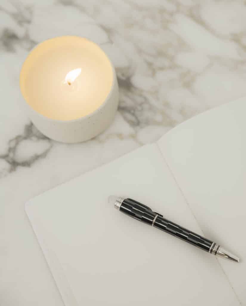 vela acesa, caderno e caneta