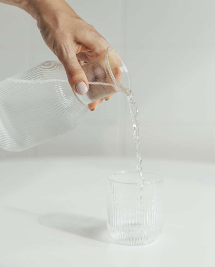 jarro a despejar agua para dentro de um copo