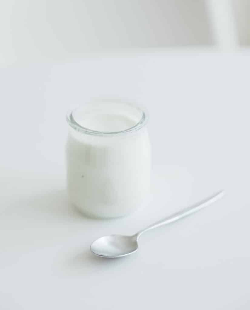 copo de iogurte e colher em cima de uma mesa
